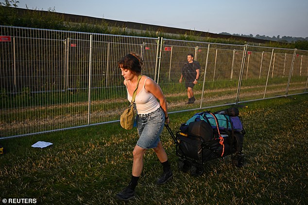 A woman hauls her luggage as revellers queue at Worthy Farm for the Glastonbury Festival in Pilton, Somerset, this morning