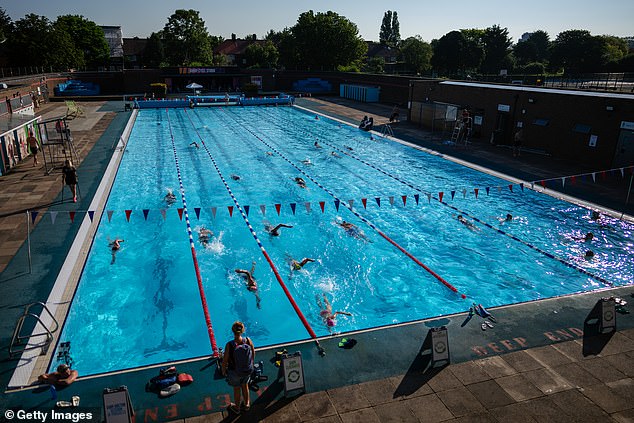 People enjoy a swim at Charlton Lido in South London this morning