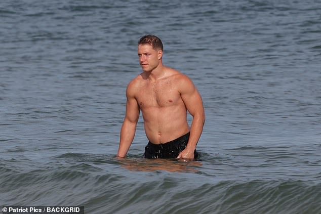 Christian went shirtless as he jumped in the ocean to cool down in the water while sporting a pair of black swim trunks