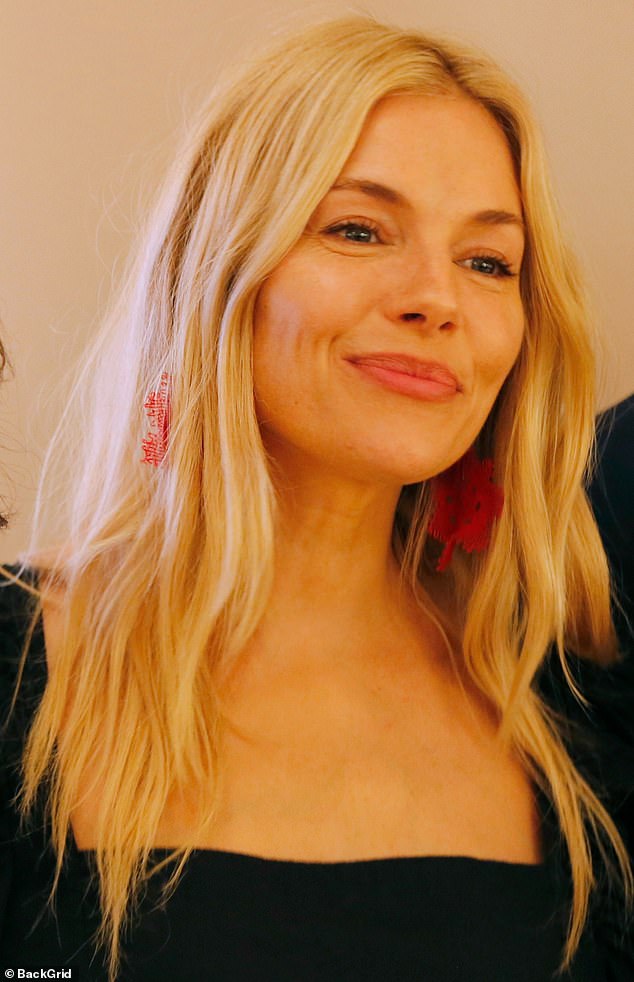 Sienna added floral-shaped maxi pendant earrings giving a touch of colour to her ensemble, beaming as she posed at the event