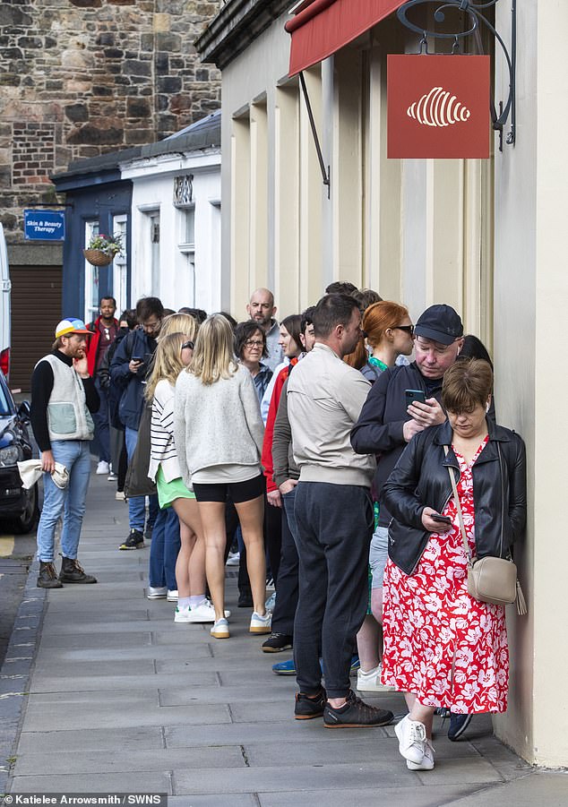 Customers keep busy while they queue outside Lannan Bakery, in Edinburgh's Stockbridge area