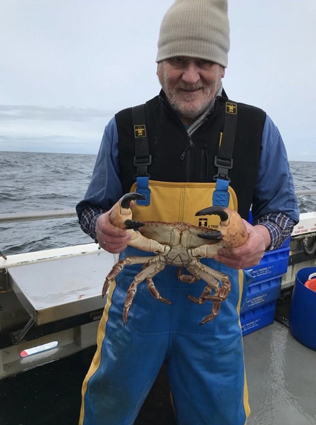 Mr Watt's father Jim holds a giant crab while fishing in the North Atlantic