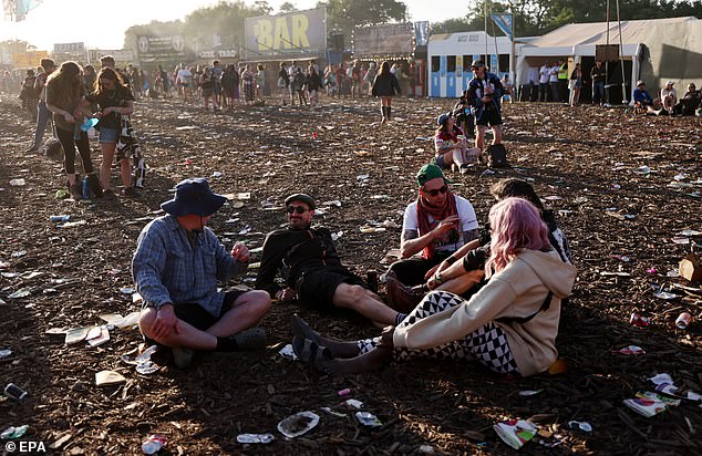 Festival-goers sit amongst rubbish on day three of the Glastonbury Festival at Worthy Farm near Pilton, Somerset