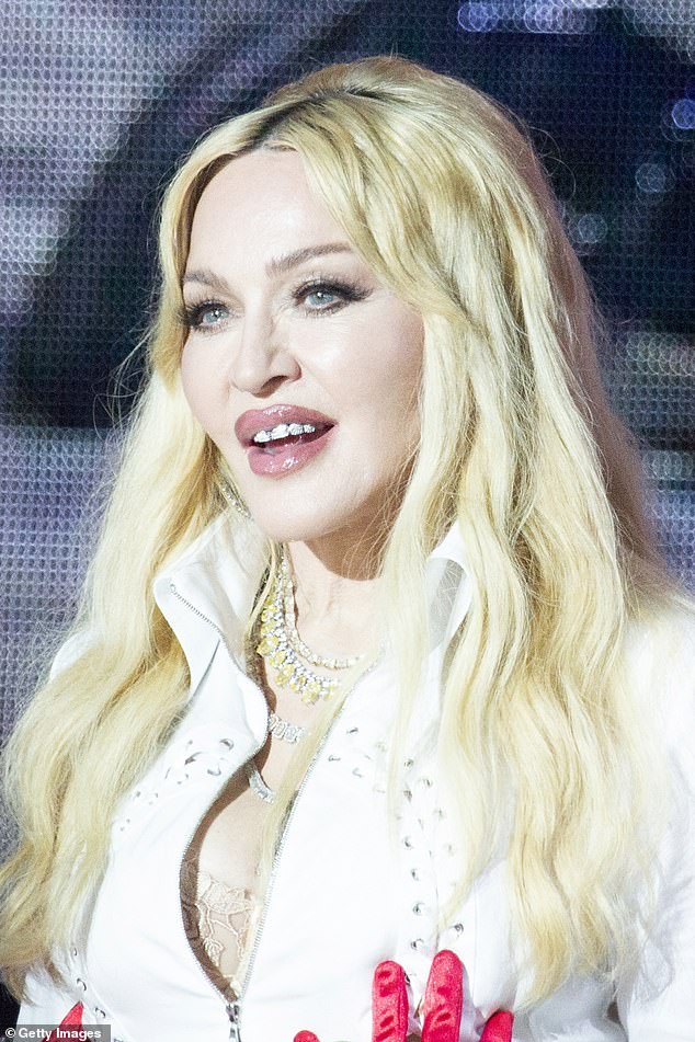 Madonna completed the look with sparkling jewel necklaces that hung in cleavage as well as a diamond grill in her mouth