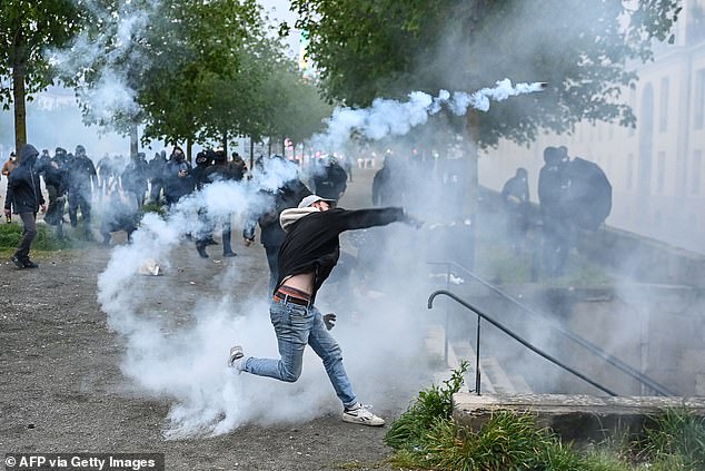 A protester throws a tear gas canister during clashes with police during a demonstration after France's Constitutional Council approved the key elements of a pension reform, in Nantes, western France, on April 14, 2023