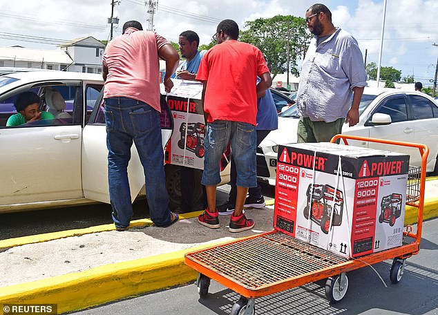 Men load electrical generators into a car ahead of the arrival of Hurricane Beryl in Bridgetown, Barbados on June 30, 2024