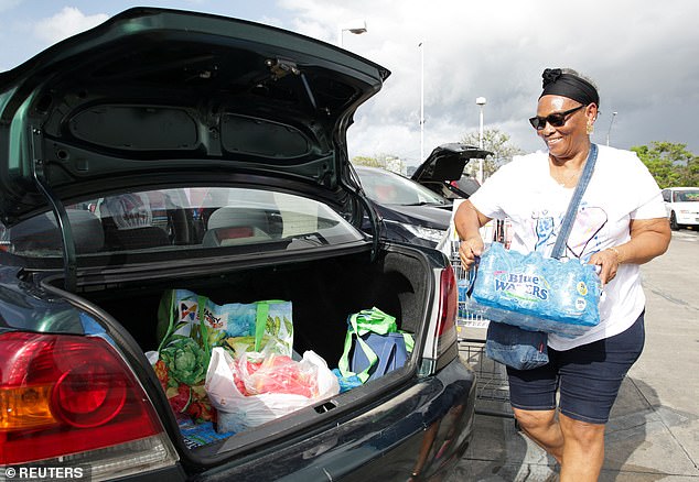 A woman carries a package of water bottles, as she prepares ahead of the arrival of Hurricane Beryl, in Port of Spain, Trinidad and Tobago on June 30, 2024.