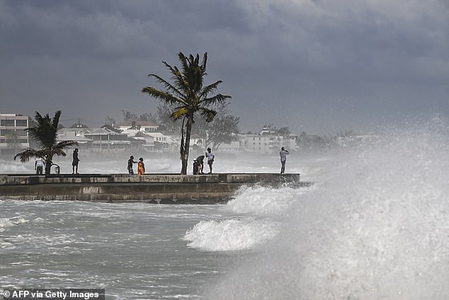 People visit a pier during a high tide after the passage of Hurricane Beryl in Oistins near Bridgetown, Barbados on July 1, 2024