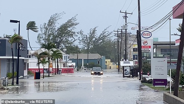 A vehicle drives through a flooded road in the aftermath of Hurricane Beryl, in Bridgetown, Barbados on July 1, 2024