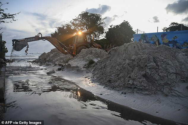 Staff from the Ministry of Transport, Works and Infrastructure clear sand from the drain after the passage of Hurricane Beryl in Oistins gardens, Christ Church, Barbados on July 1, 2024