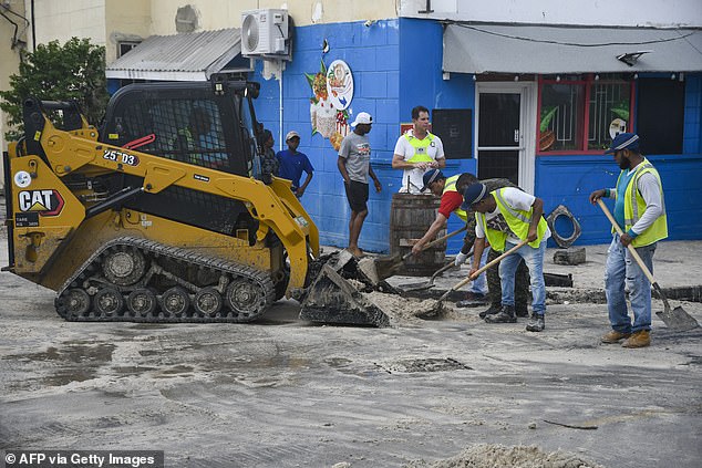 Workers clear sand from the south coast's main road after the passage of Hurricane Beryl in Christ Church, Barbados, on July 1, 2024