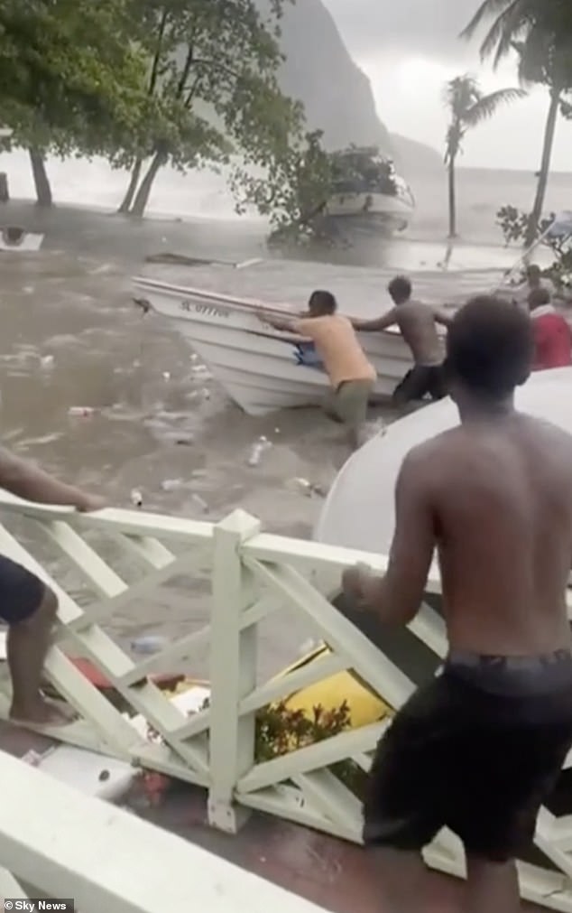 Locals are seen pushing a boat along a flooded street in Grenada after Hurricane Beryl battled the island on Monday