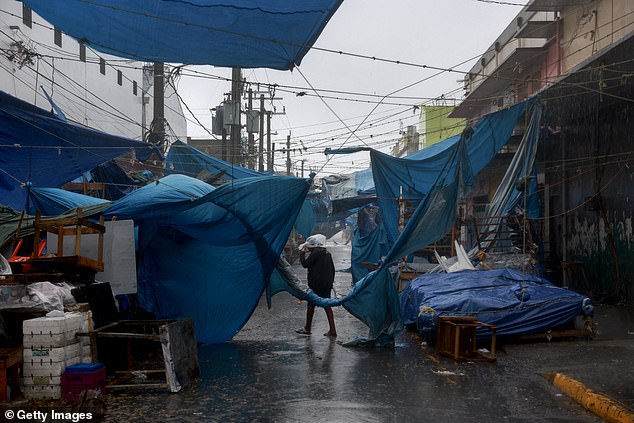 A person makes their way through the wind and rain from Hurricane Beryl in Kingston, Jamaica