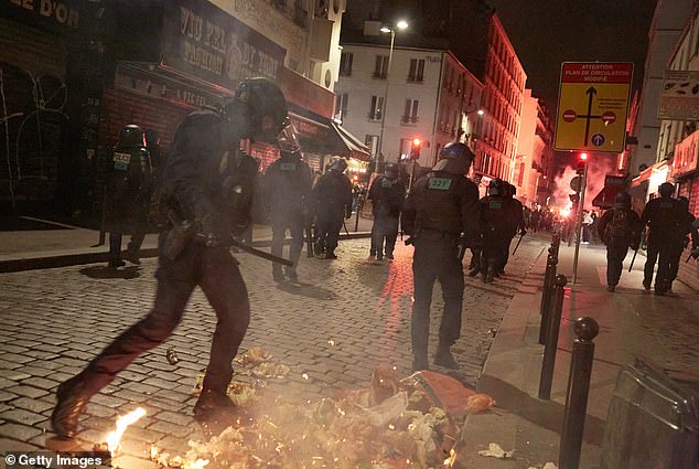 Anti-riot police officers push back protesters who had set piles of rubbish alight