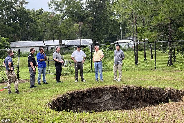 This photo shows a sinkhole that in 2013 fatally swallowed a man sleeping in his own house. The sinkhole has reopened for a third time, this time behind chain-link fencing and doing no harm to people or property