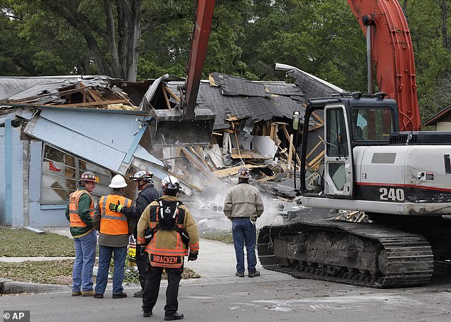 Demolition experts watch as the home, destroyed, March 3, 2013, after a sinkhole opened up underneath it late evening swallowing Bush, 37, in Seffner