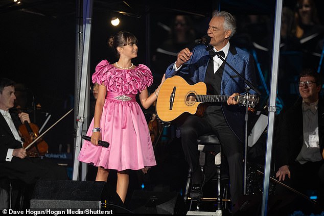 Virginia, 12, wore a beautiful pink dress and lay a hand on Andrea's elbow as he sat on a stool with a guitar