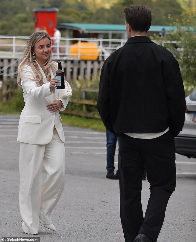 She toted her essentials around in a white woven clutch bag and styled her locks in voluminous waves as she prepared for her big day