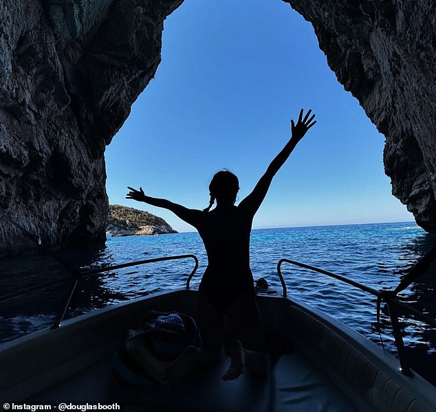 On a boat, Douglas captured Bel's silhouette as she stretched her arms wide at the bow and the two went through a cave