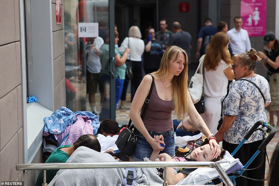 A woman holds the hand of a young patient outside Ohmatdyt Children's Hospital today