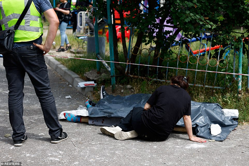 A woman sits next to the bodies of her relatives killed during a Russian missile strikes, July 8