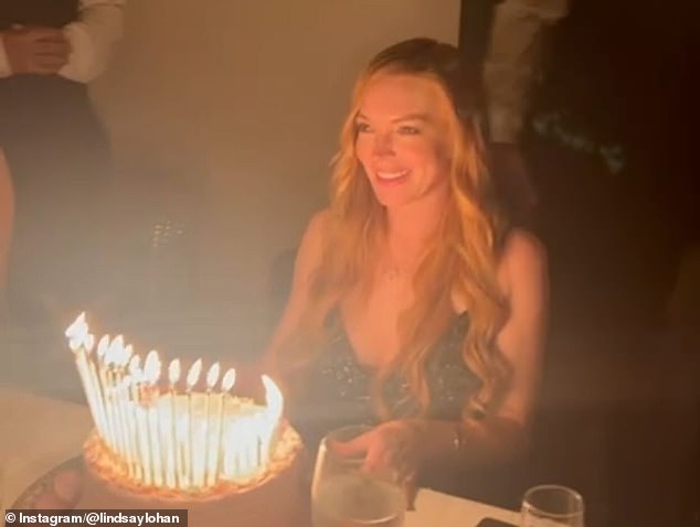 Lohan beamed while she looked at her lit-up birthday cake