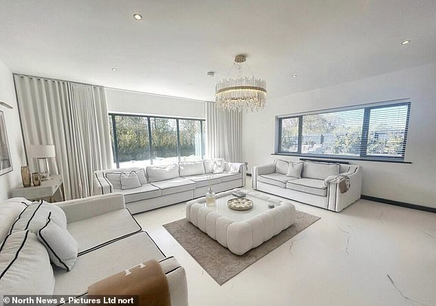 Three white sofas are situated around a large coffee table in the lounge