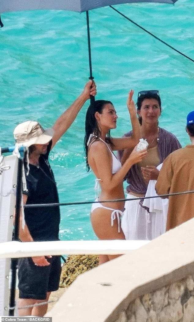 A crew member held an umbrella to protect the model from the scorching weather