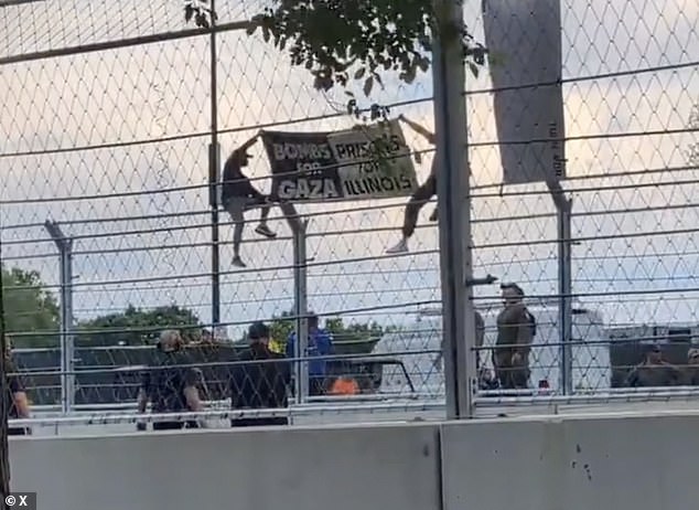 The protestors are seen up on the fence with the flag that was later ripped from their hands