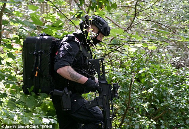 An officer walks through foliage in Lavender Hill Cemetery this afternoon