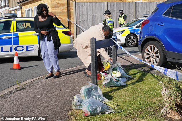 A woman delivers floral tributes near to the scene in Bushey, Hertfordshire