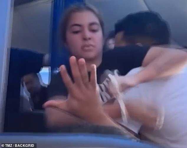 Video recorded by another traveler began after the crew restrained her wrists with zip-ties and she was wrestling with three of them