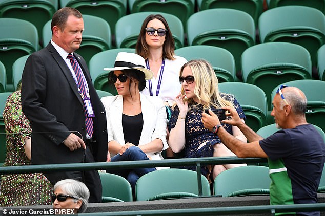 A spectator is reprimanded by a security guard after taking a photograph near the Duchess of Sussex