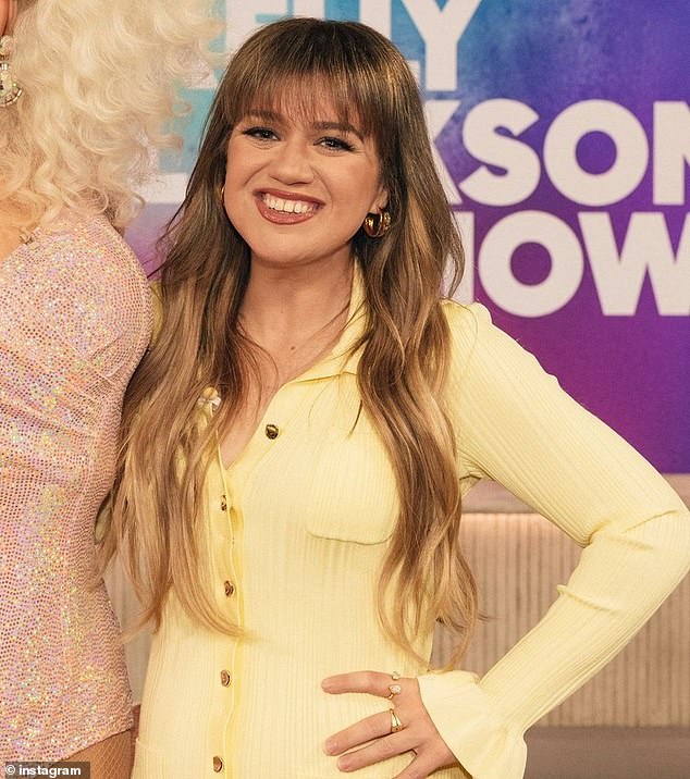 Kelly coordinated in a tailored, long-sleeved yellow dress featuring cold buttons down the entire length of the garment