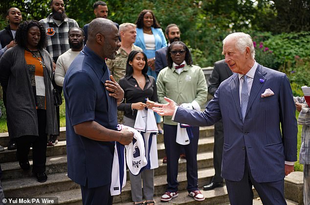 The monarch, 75, opted for a pinstripe suit and grinned as he proudly brandished an England shirt with performer and musician, 51, at St James's Palace on Friday