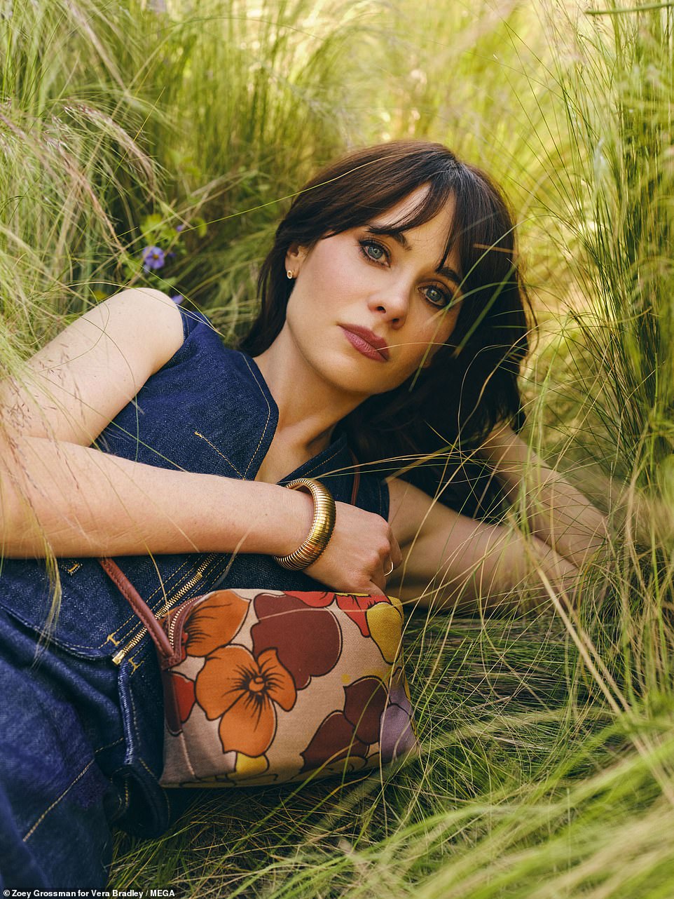 She showcased  showcased a small lavender, brown, red and gold cross over bag as she lay in the grass