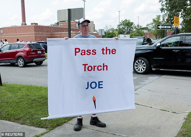 Protester Tom Moran holds a banner outside President Biden's Detroit rally on July 12