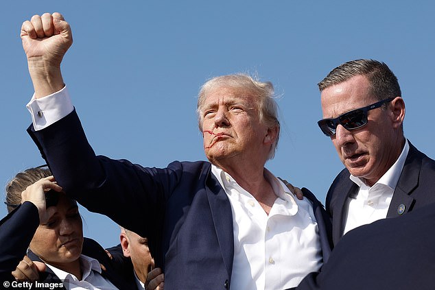 Donald Trump is pictured with blood on his face moments after shots rang out at a rally in Butler, Pennsylvania, on Saturday