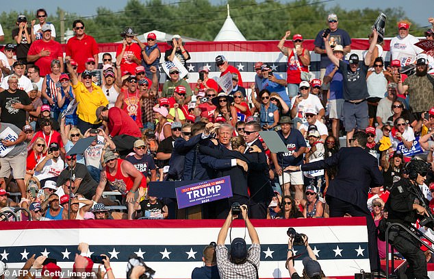 A wider shot shows Trump being surrounded by Secret Service agents on the stage while stunned supporters look on. Security officials could be heard screaming 'the shooter is down' in the moments after gunfire erupted