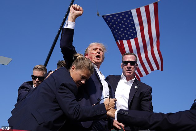 Former President Donald Trump is surrounded by U.S. Secret Service agents after being shot at a campaign rally on Saturday, July 13, 2024, in Butler, Pa