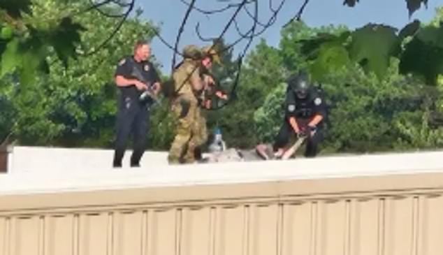 Law enforcement officials stand over a body on the roof of a building just outside the Butler Farm Grounds. This is believed to be the gunman who shot Donald Trump