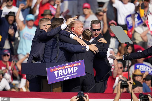 A bloodied Trump is surrounded by Secret Service personnel moments after being shot