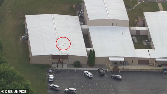 14/07/2024 - Pennsylvania -  Local news helicopter images of the dead gunman on the roof of a building overlooking the podium. Secret Service agents have rushed former President Donald Trump off stage after what sounded like gunshots rang out at a rally in Pennsylvania. Footage showed him grimace and raise a hand to his ear, before ducking as sharp cracks - apparently shots - broke out. He was quickly swarmed by secret service agents and rushed off stage to a waiting vehicle. In a statement Trump's campaign said he was "fine" and was being "checked out" at a local medical facility. "President Trump thanks law enforcement and first responders for their quick action during this heinous act," spokesman Steven Cheung said. The former president appeared to have blood on his right ear and raised a fist as he was bundled off stage and into a car. Armed police took to the podium soon after. In a statement, the Secret Service said Trump was safe and that measures for his protection had been im