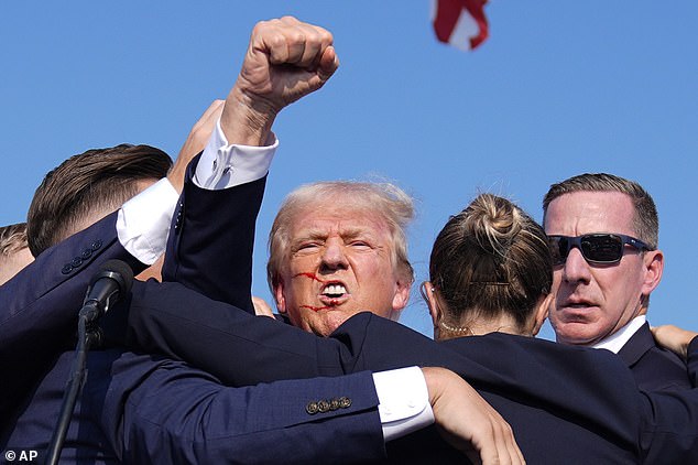 Trump pumps his fist as he's surrounded by secret service agents