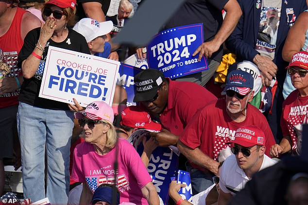 Members of the MAGA crowd duck and grimace as loud bangs are heard