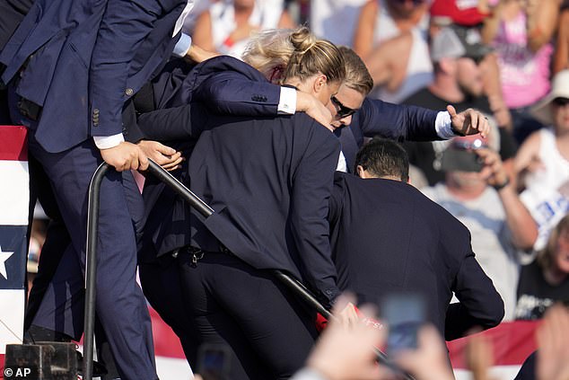 Republican presidential candidate former President Donald Trump is helped off the stage by US Secret Service agents at a campaign event in Butler