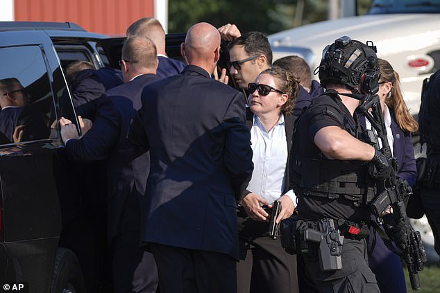 Armed officers and Secret Service agents surround the SUV as Trump is placed into the vehicle