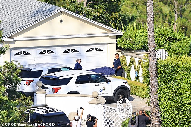 The coroner is seen retrieving fitness guru Simmons' body from his LA home over the weekend