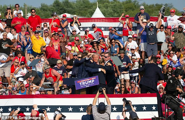 A wider shot shows Trump being surrounded by Secret Service agents on the stage while stunned supporters look on. Security officials could be heard screaming 'the shooter is down' in the moments after gunfire erupted