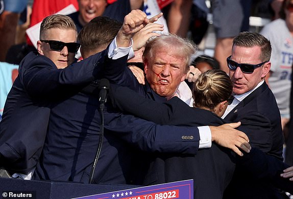 FILE PHOTO: Republican presidential candidate and former U.S. President Donald Trump gestures with a bloodied face while he is assisted by U.S. Secret Service personnel after he was shot in the right ear during a campaign rally at the Butler Farm Show in Butler, Pennsylvania, U.S., July 13, 2024. REUTERS/Brendan McDermid/File Photo